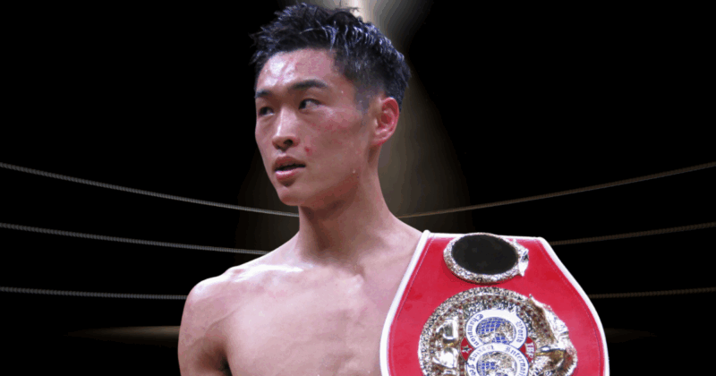 IBF世界バンタム級王座のベルトを肩にかけた西田凌佑選手の試合後の姿。リング上で上半身裸になり、赤いチャンピオンベルトを右肩に掛けている。汗で濡れた黒髪を上げ、真剣な表情で前方を見つめている。