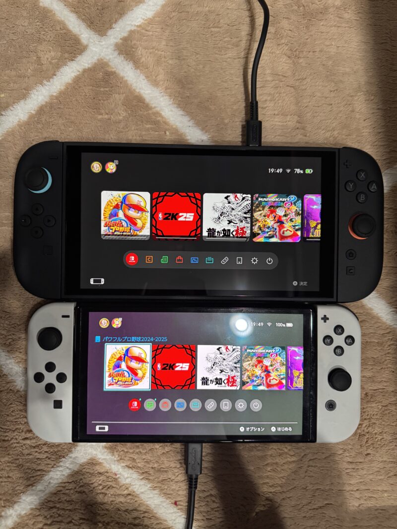 Nintendo Switch 2(上)とNintendo Switch有機EL(下)の画面比較写真。両方とも同じゲームタイトルが表示されたHOMEメニューが映し出されており、画面サイズと表示品質の違いが明確に分かる